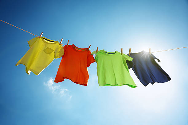 Rainy Season: T-shirts hanging on a clothesline in front of blue sky and sun