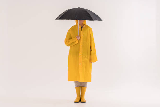 Rainy Season: Middle adult woman in yellow raincoat and rain boots.